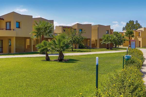 Außenbereich des VOI Arenella Resorts mit gelben Gebäuden und gepflegtem Rasen.