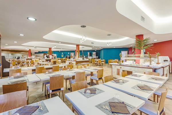 Innenansicht des Restaurants im VOI Arenella Resort mit blauen und roten Wänden und runden Säulen.