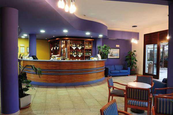 Rezeption des VOI Arenella Resorts mit Bar, gelben Wänden und blauen Möbeln.