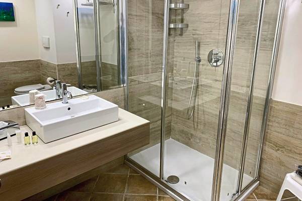 Badezimmer im VOI Arenella Resort mit Dusche, Waschbecken und Spiegel.