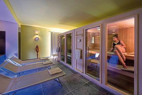 Saunabereich im VOI Arenella Resort mit Liegen und einer Frau in der Sauna.