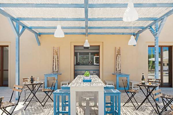 Terrasse des VOI Arenella Resort mit blauen Stühlen und Tischen unter einem Dach.