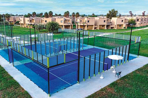 Luftaufnahme des VOI Arenella Resorts Tennisplatz mit umzäunten Feldern, einem Sonnenschirm und einem Stuhl