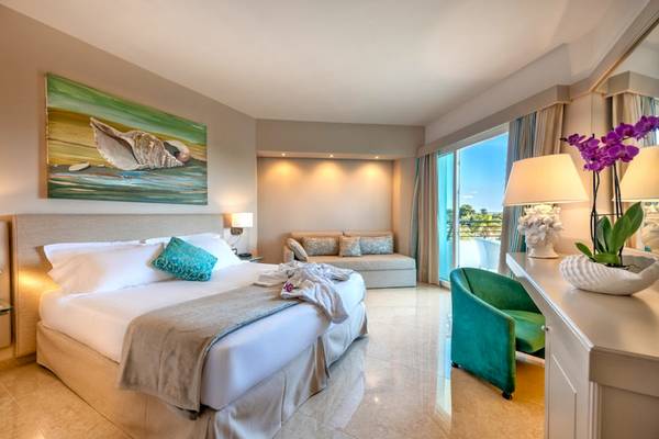Ein elegantes Hotelzimmer im Acacia Palace mit einem großen Bett, einem Sofa und einem Panoramafenster.