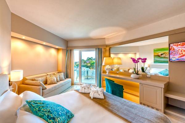Suite-Zimmer im Acacia Palace Hotel mit großem Bett, Sofa und Terrassenzugang.