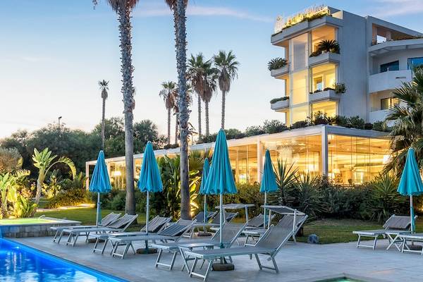 Acacia Palace Hotel mit Swimmingpool und Sonnenliegen bei Sonnenuntergang.