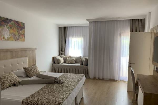 Doppelbett-Zimmer im Cesars Side Hotel mit Bett, Sofa und Fenstern mit Vorhängen.