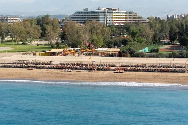 Strandansicht des Megasaray Resort Side mit vielen Liegen und einem großen Hotelgebäude im Hintergrund.