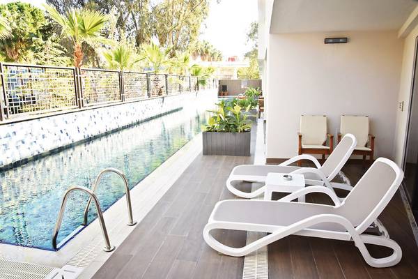 Poolbereich mit weißen Lounge-Stühlen und Pflanzen am Seaden Quality Resort & Spa.