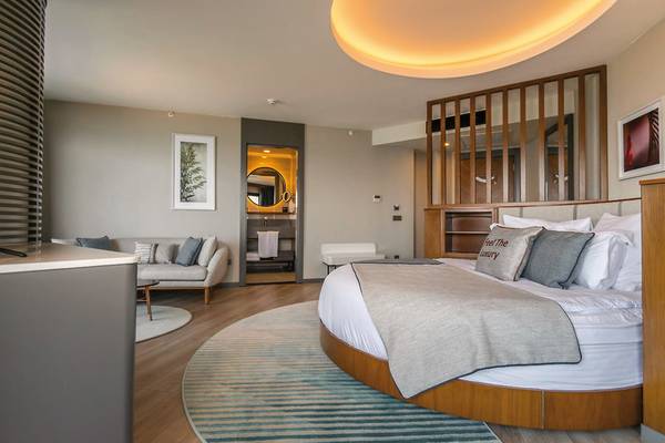 Schlafzimmer im Seaden Quality Resort & Spa mit Rundbett, Sofa, Badezimmerspiegel und Dekor.