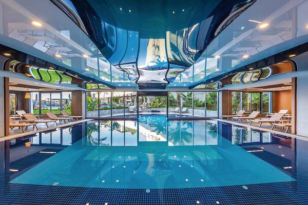 Innenpool des Seaden Quality Resort & Spa mit Liegestühlen und Glaswänden.