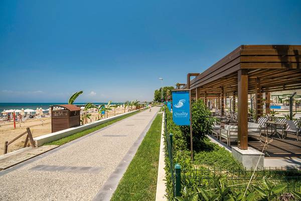 Außenbereich des Seaden Quality Resort & Spa mit Gehweg, Strand und Loungebereich.