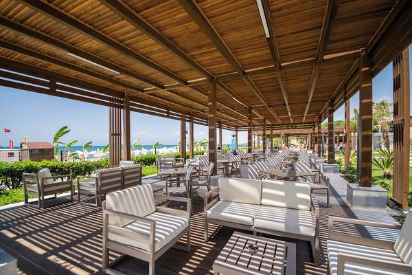 Außenbereich des Seaden Quality Resort & Spa mit vielen Sitzgelegenheiten und Blick auf den Strand.