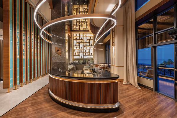 Innenansicht der Bar im Seaden Quality Resort & Spa mit geschwungener Theke und modernen Möbeln.