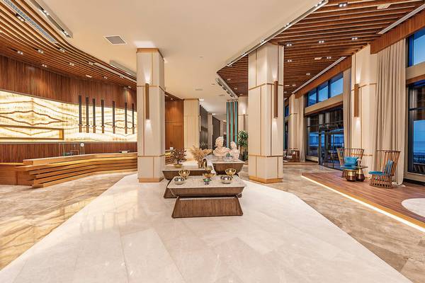 Lobby des Seaden Quality Resort & Spa mit Marmorboden, Holzelementen und großen Fenstern.