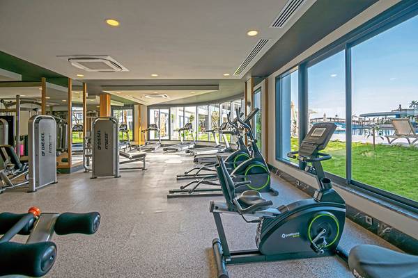 Fitnesscenter im Seaden Quality Resort & Spa mit vielen Geräten und großen Fenstern.
