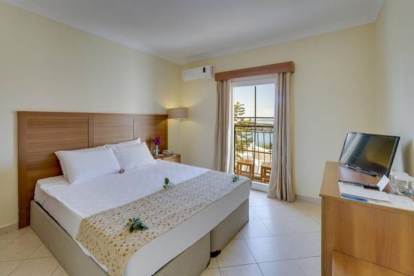 Hotelzimmer im Larissa Bodrum View Resort mit einem großen Bett, Balkon und Aussicht auf den See.