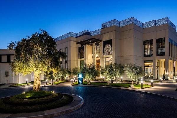 Außenansicht des Intercontinental Doha Beach & Spa bei Nacht mit beleuchteten Bäumen und Gebäuden.