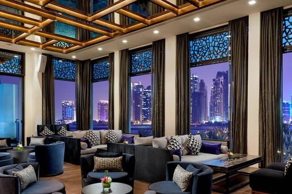 Hotellobby mit luxuriösen Sofas, Tischen, großen Fenstern und Stadtaussicht in Doha.