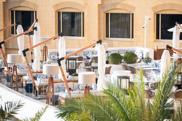 Außenbereich des Intercontinental Doha Beach & Spa Hotels mit Sofas, Tischen und Palmen