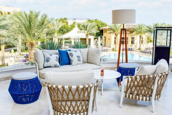 Außenbereich des Intercontinental Doha Beach & Spa Hotels mit Möbeln, einem Swimmingpool und Palmen.
