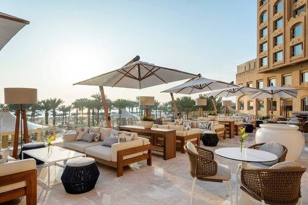 Terrasse des Intercontinental Doha Beach & Spa mit Möbeln und Sonnenschirmen