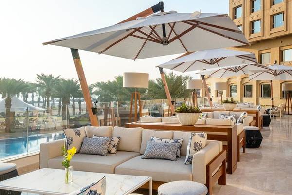 Hotelloungebereich mit Sofas, Tischen und Schirmen am Pool des Intercontinental Doha Beach & Spa