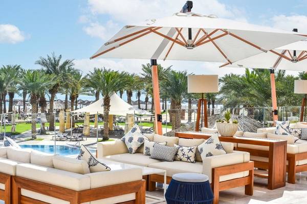 Außenbereich des Intercontinental Doha Beach & Spa Hotels mit Loungemöbeln und Sonnenschirmen neben dem Pool.