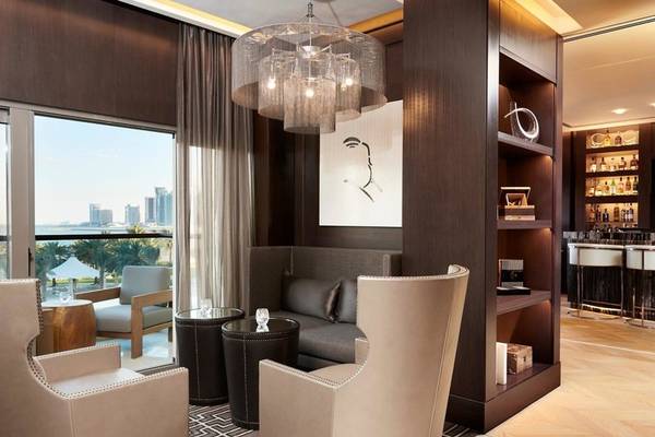 Interieur eines Hotel-Lounges mit moderner Einrichtung, Couch, Sesseln, und einem Blick auf die Stadt.