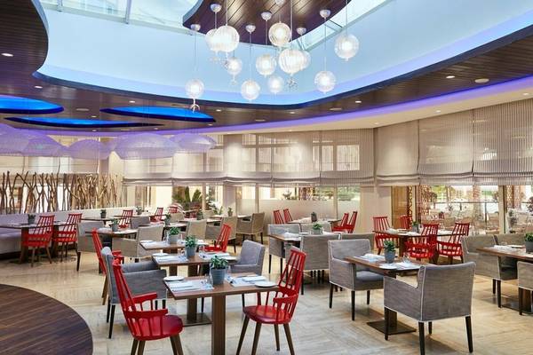 Innenansicht des Restaurants im Intercontinental Doha Beach & Spa Hotel mit modernen Möbeln und hängenden Lampen.