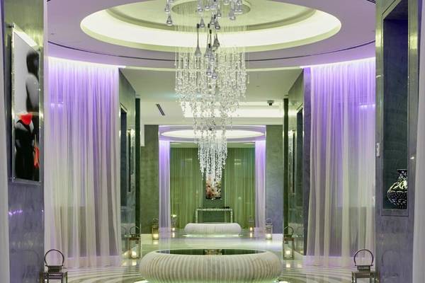 Innenbereich des Intercontinental Doha Beach & Spa Hotels mit einer großen Kristallleuchte und einer zentralen Wasserskulptur.