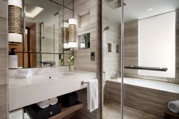 Innenansicht eines Badezimmers im Intercontinental Doha Hotel mit Spiegel, Waschbecken, Handtüchern und Badewanne.