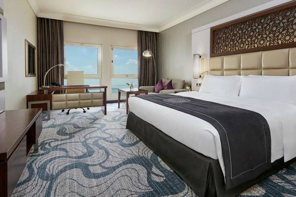 Hotelzimmer im Intercontinental Doha Beach & Spa mit großem Bett, Schreibtisch und Meerblick.