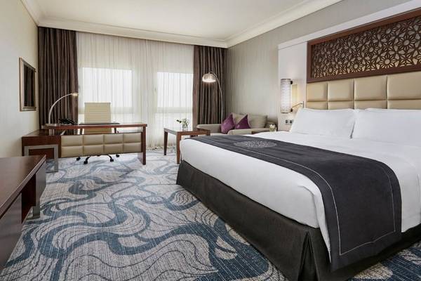 Hotelzimmer im Intercontinental Doha Beach & Spa mit Bett, Schreibtisch und Sofabereich.