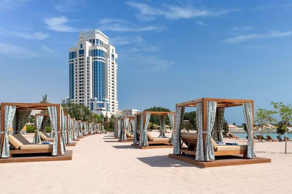 Reihe von Strand-Lounge-Betten vor dem Ritz-Carlton Doha Hotel