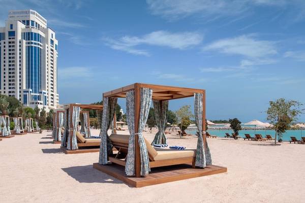 Außenbereich des Ritz-Carlton Doha mit luxuriösen Strandbetten und Blick auf das Meer.