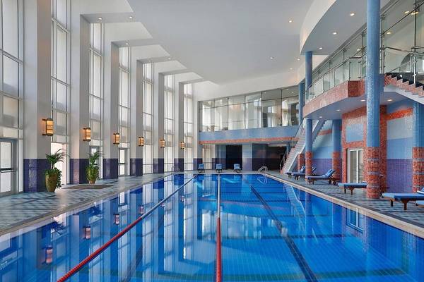 Innenpool im Ritz-Carlton Doha Hotel mit blauen Fliesen und roten Trennlinien.