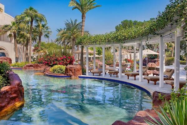 Poolbereich des Ritz-Carlton Doha Hotels mit Loungestühlen und Pflanzen.