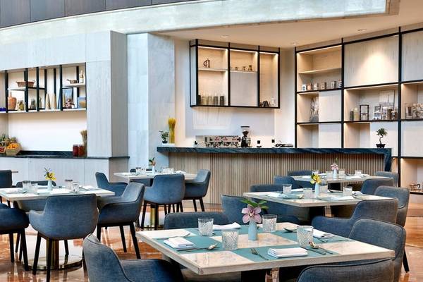 Innenansicht des Restaurants im Ritz-Carlton Doha mit blauen Stühlen und Tischen.