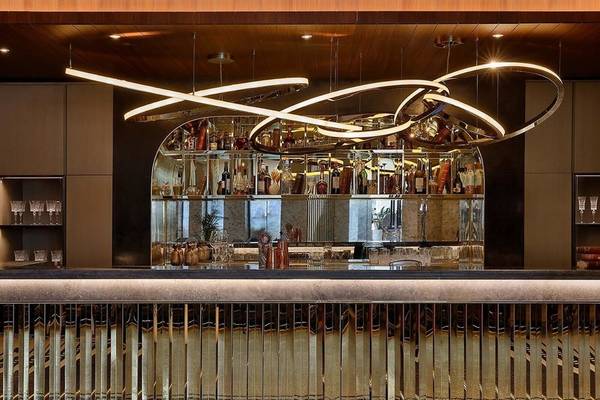 Innenansicht der Bar im Ritz-Carlton Doha Hotel mit goldenen Spiegeln und Glastheke.