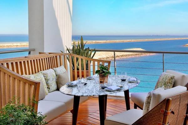 Balkon des Ritz-Carlton Doha mit Blick auf das Meer und einer Tischdekoration.