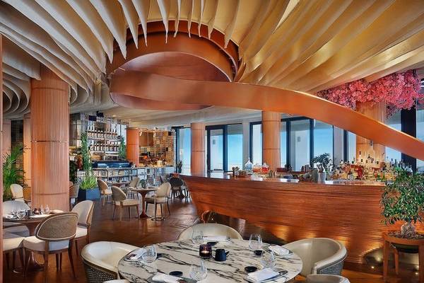 Innenansicht des Restaurants im Ritz-Carlton Doha mit geschwungenen Holzdecken und modernen Möbeln.