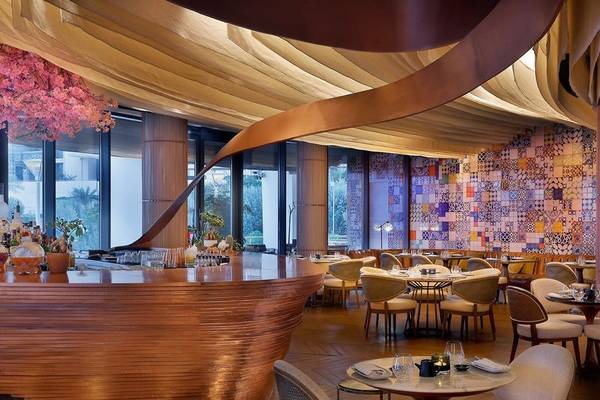 Innenbereich eines Restaurants im Ritz-Carlton Doha mit einer geschwungenen Theke und bunten Wandfliesen.