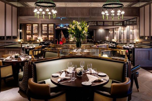 Innenansicht des Restaurants im Sheraton Doha Resort Convention Hotel mit gerahmten Sitzbänken, Tischdecken und Weinflaschen.