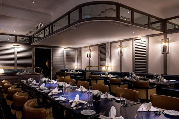 Innenansicht des Restaurants im Sheraton Doha Resort Convention Hotel mit langen Tischen, Lederstühlen und Tischdekorationen.