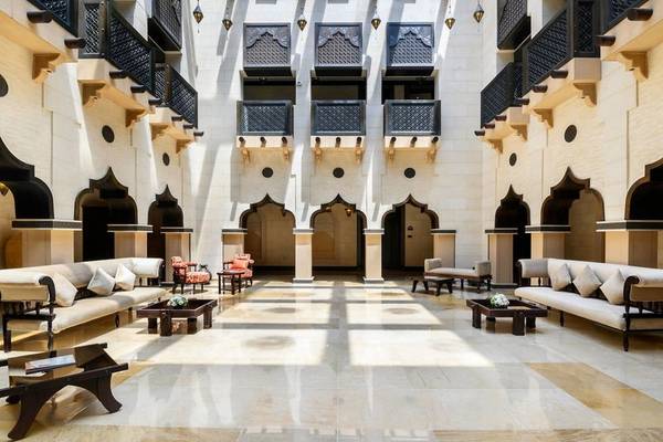 Lobby des Sharq Village und Spa, ein Ritz Carlton Hotel mit weißen Sofas und Tischen, Säulen und schwarzen Balkonen.