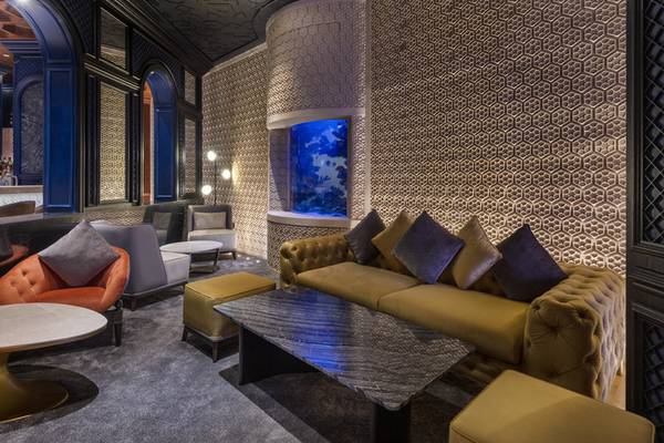 Loungebereich des Sharq Village and Spa Hotels mit geometrischen Wandmustern und einem Aquarium.