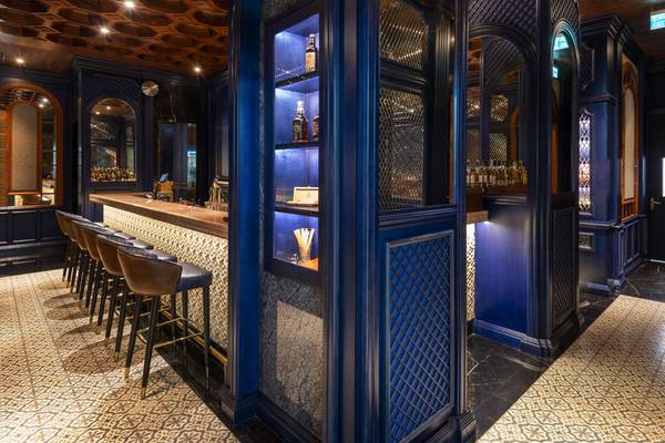 Die Bar im Sharq Village and Spa, A Ritz Carlton Hotel, mit blauen Wänden und gemusterten Böden.