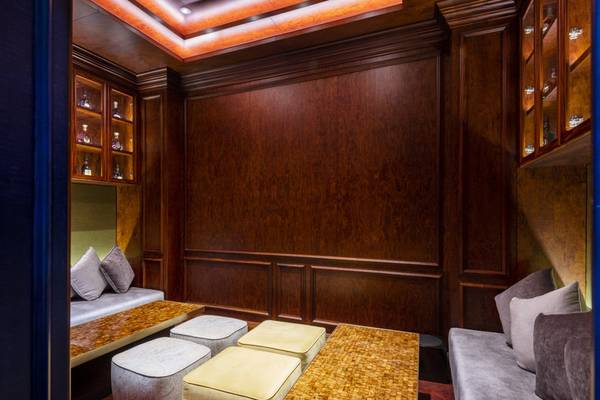 Loungebereich im Sharq Village and Spa, A Ritz Carlton Hotel mit braunen Holzwänden, Sofas und Tischen.
