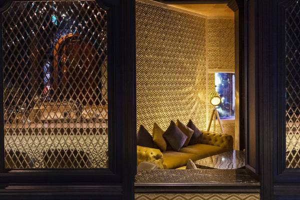 Loungebereich des Sharq Village and Spa, A Ritz Carlton Hotel mit goldenen Wandmustern und Möbeln.